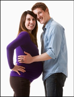 Man embracing pregnant woman, studio shot. Photo : Mike Kemp