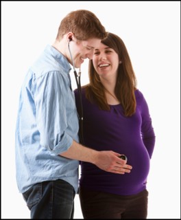 Man listening of heartbeating on belly of pregnant woman, studio shot. Photo : Mike Kemp
