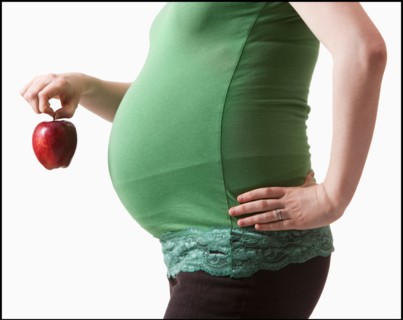 Pregnant woman holding red apple. Photo : Mike Kemp