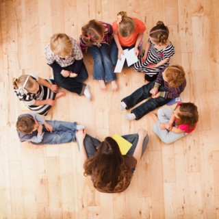 Children (2-3, 4-5) sitting in circle around teacher, directly above. Photo : Mike Kemp