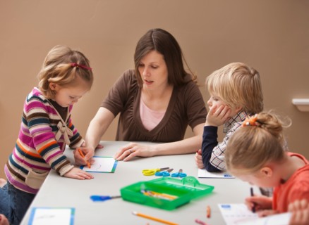 Mid adult woman teaching children (2-3, 4-5) drawing in kindergarten. Photo : Mike Kemp
