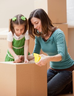 Mother with daughter (4-5) closing cardboard box. Photo : Mike Kemp