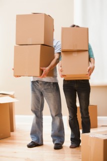 Mid adult couple carrying cardboard boxes. Photo : Mike Kemp