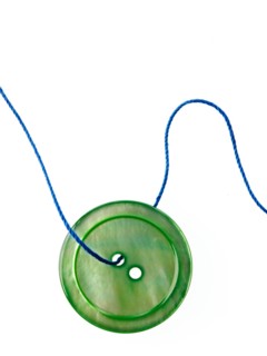 Studio shot of single green button on thread. Photo : David Arky