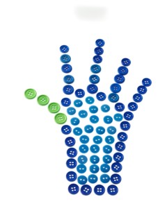 Studio shot of blue and green buttons arranged in human hand. Photo : David Arky