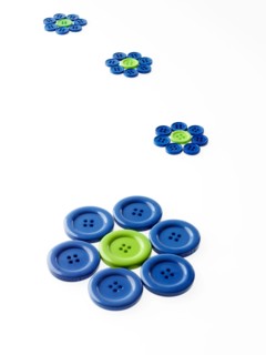 Studio shot of blue and green buttons arranged in flower head. Photo : David Arky