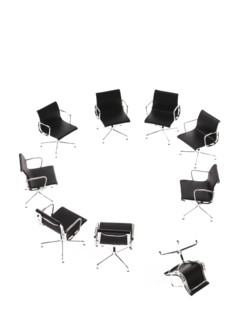 Corporate chairs forming circle on white background, one upside down. Photo : David Arky