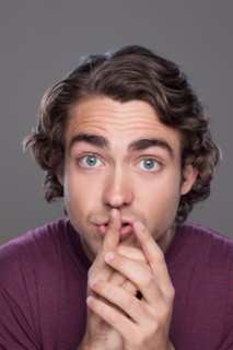 Studio shot of young man with finger on his lips. Photo : Rob Lewine