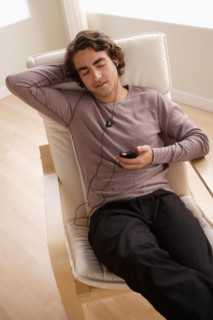Young man listening music on armchair. Photo : Rob Lewine