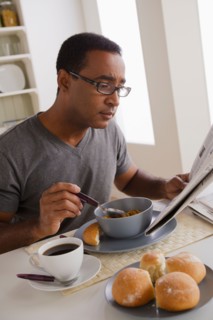 Mature man eating breakfast and reading newspaper. Photo : Rob Lewine