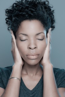 Studio shot of young woman with hands covering ears. Photo : Rob Lewine