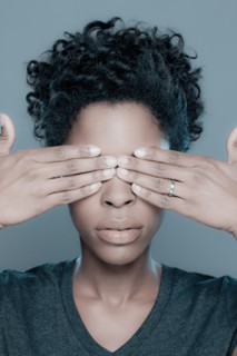 Studio shot of young woman with hands covering eyes. Photo : Rob Lewine