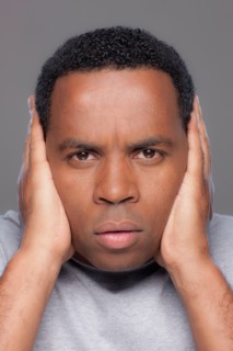 Studio shot of mid adult man covering ears. Photo : Rob Lewine