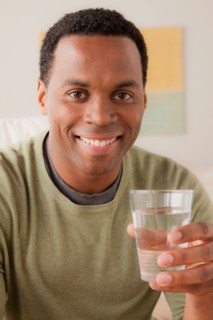 Portrait of smiling man holding glass of water. Photo : Rob Lewine