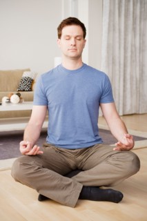 Mid adult man meditating at home. Photo : Rob Lewine