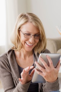 Smiling mid adult woman using digital tablet. Photo : Rob Lewine