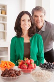 Portrait of mature couple with snacks on table. Photo : Rob Lewine