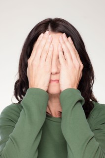 Studio portrait of mature woman covering eyes. Photo : Rob Lewine
