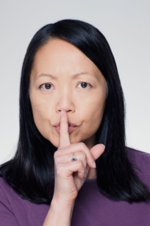 Studio portrait of mature woman with finger on lips. Photo : Rob Lewine