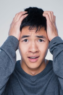 Studio portrait of young man with head in hands. Photo : Rob Lewine