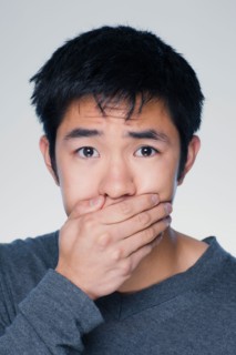 Studio portrait of young man covering mouth. Photo : Rob Lewine