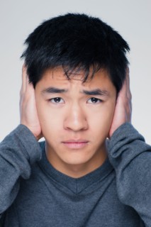 Studio portrait of young man covering ears. Photo : Rob Lewine