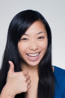 Studio portrait of young woman showing thumbs up sign. Photo : Rob Lewine