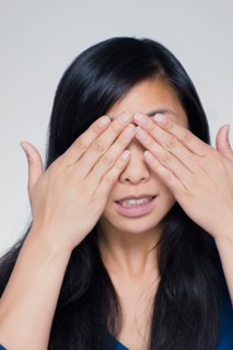 Studio portrait of young woman covering eyes. Photo : Rob Lewine