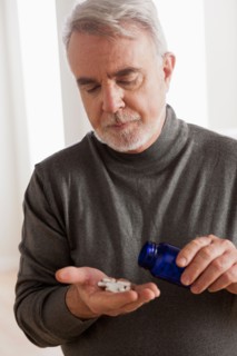 Senior men holding pills. Photo : Rob Lewine