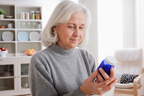 Senior women reading label on medicine bottle. Photo : Rob Lewine
