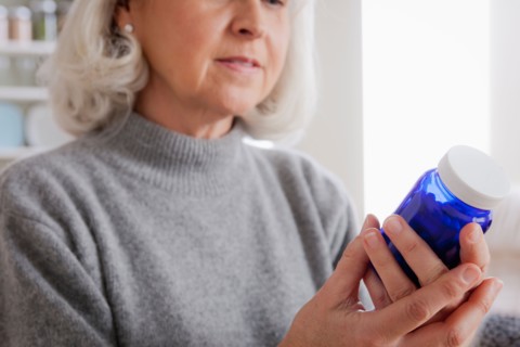 Senior women reading label on medicine bottle. Photo : Rob Lewine