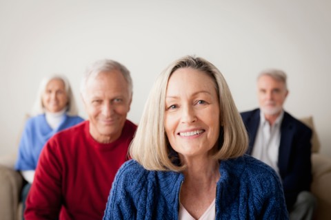 Two senior couples on sofa, smiling woman in foreground. Photo : Rob Lewine