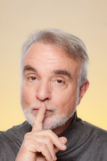 Studio shot of senior man with finger on her lips. Photo : Rob Lewine