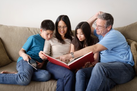 Family watching photo album together. Photo : Rob Lewine