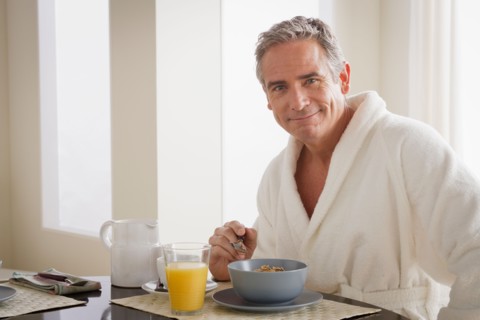 Man in bathrobe having cereal for breakfast. Photo : Rob Lewine