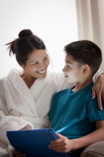 Mother embracing son using laptop. Photo : Rob Lewine
