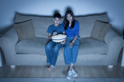 Brother and sister (10-11, 12-13) watching television. Photo : Rob Lewine