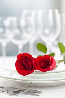 Dishes and cutlery prepared for meal decorated with red roses. Photo : Elena Elisseeva