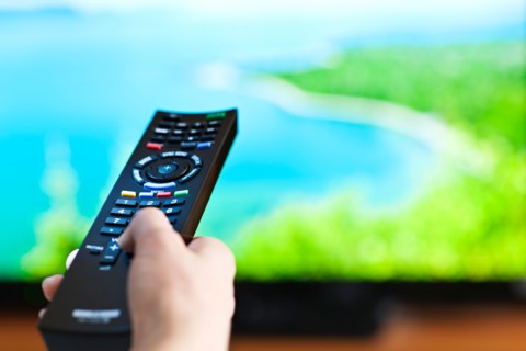 Human hand holding remote control . Photo : Elena Elisseeva