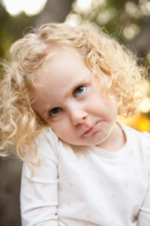 Outdoor portrait of cute blonde girl (4-5) making face. Photo : Jessica Peterson
