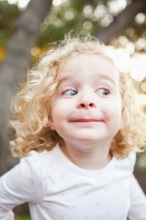 Outdoor portrait of cute blonde girl (4-5) pulling funny faces. Photo : Jessica Peterson