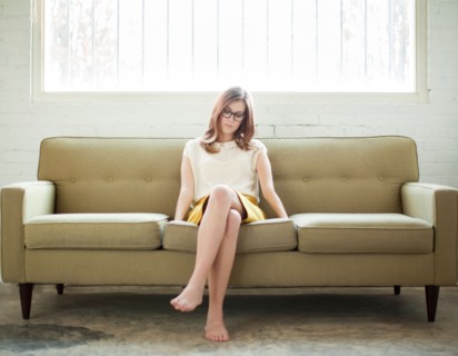 Young woman sitting on sofa. Photo : Jessica Peterson