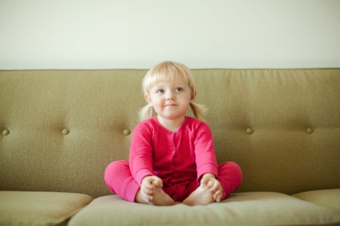 Portrait of baby girl (18-23 months) sitting on sofa. Photo : Jessica Peterson