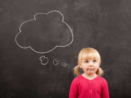 Portrait of baby girl (18-23 months) in front of blackboard. Photo : Jessica Peterson