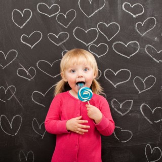 Portrait of baby girl (18-23 months) eating lollipop. Photo : Jessica Peterson