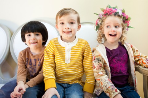 Studio Shot portrait of three children (4-5, 6-7) sitting side by side. Photo : Jessica Peterson