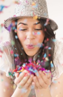 Portrait of young woman blowing confetti.