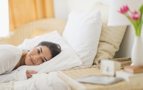 Portrait of young woman lying in bed.