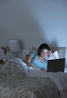 Young woman using laptop in bed.