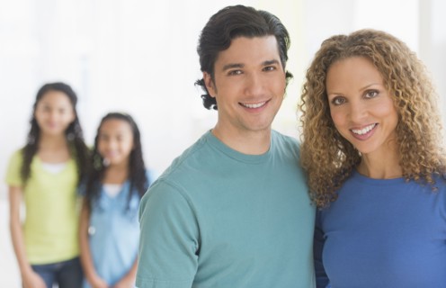 Portrait of parents with daughters (10-13) in background.